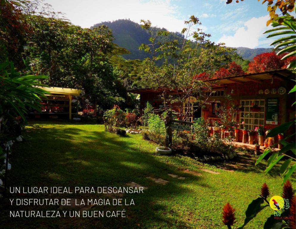 um jardim em frente a um edifício com montanhas ao fundo em Eco Lodge Villa Laura 