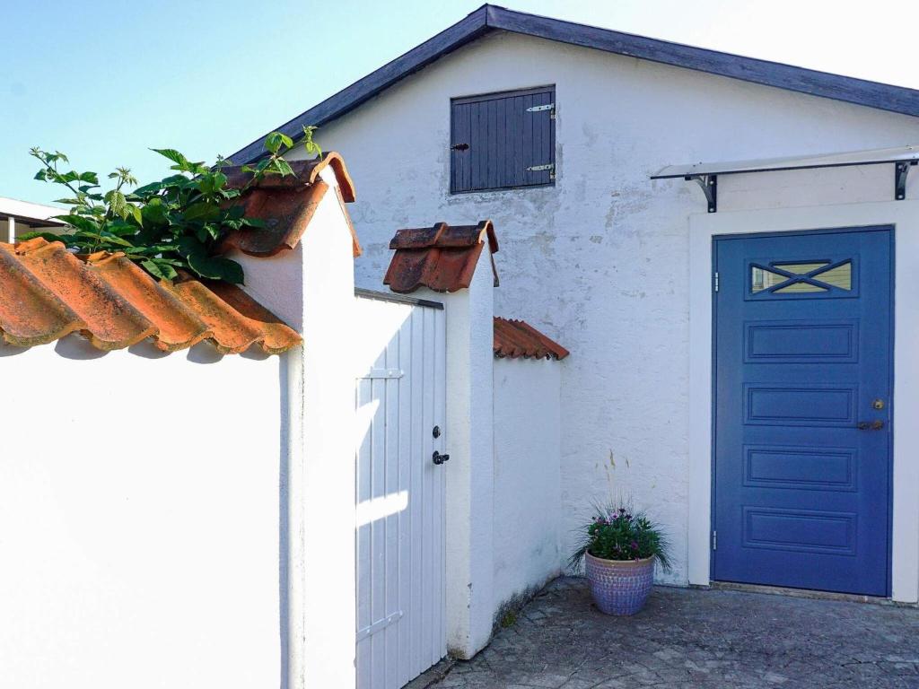 a white house with a blue door and a fence at Holiday home SÖLVESBORG XVI in Sölvesborg