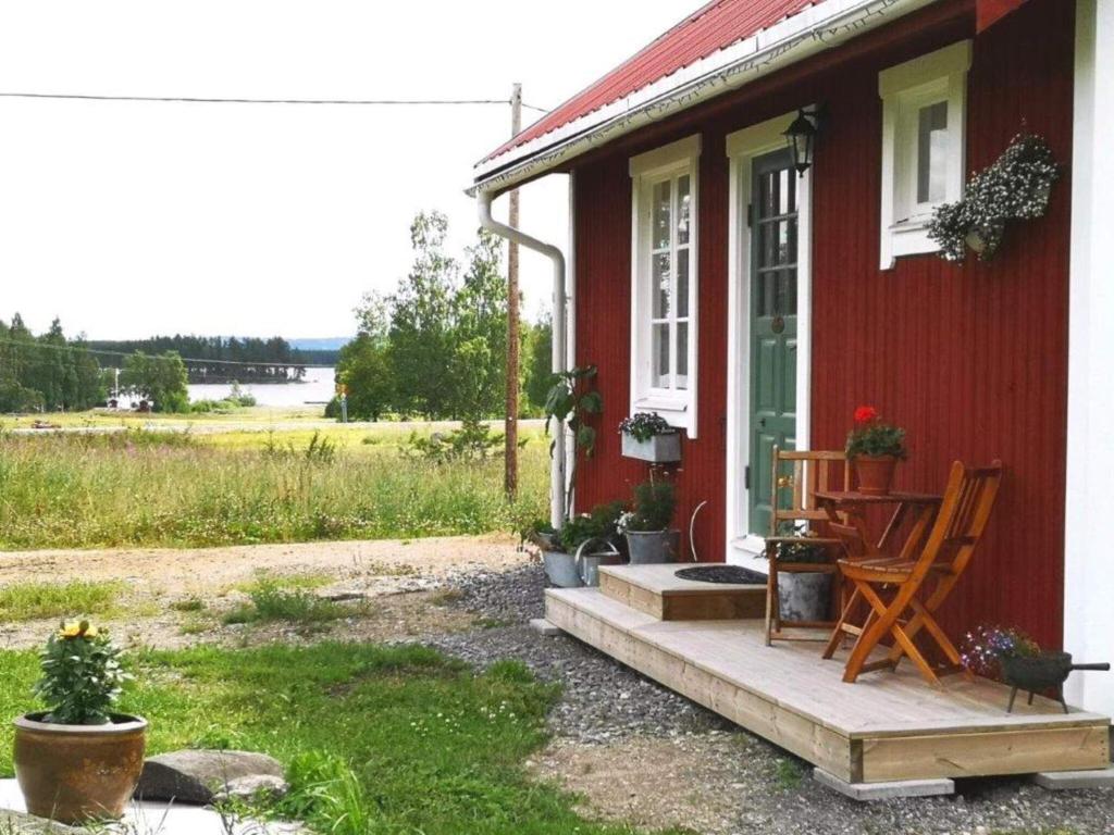 a red house with a porch with a table and chairs at Holiday home RAMSJÖ III in Ramsjö