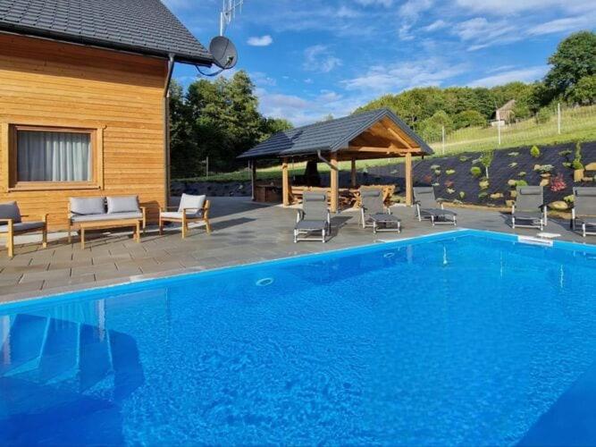 a large swimming pool with chairs and a gazebo at Comfortable holiday home with a swimming pool for 12 people in Iwierzyce