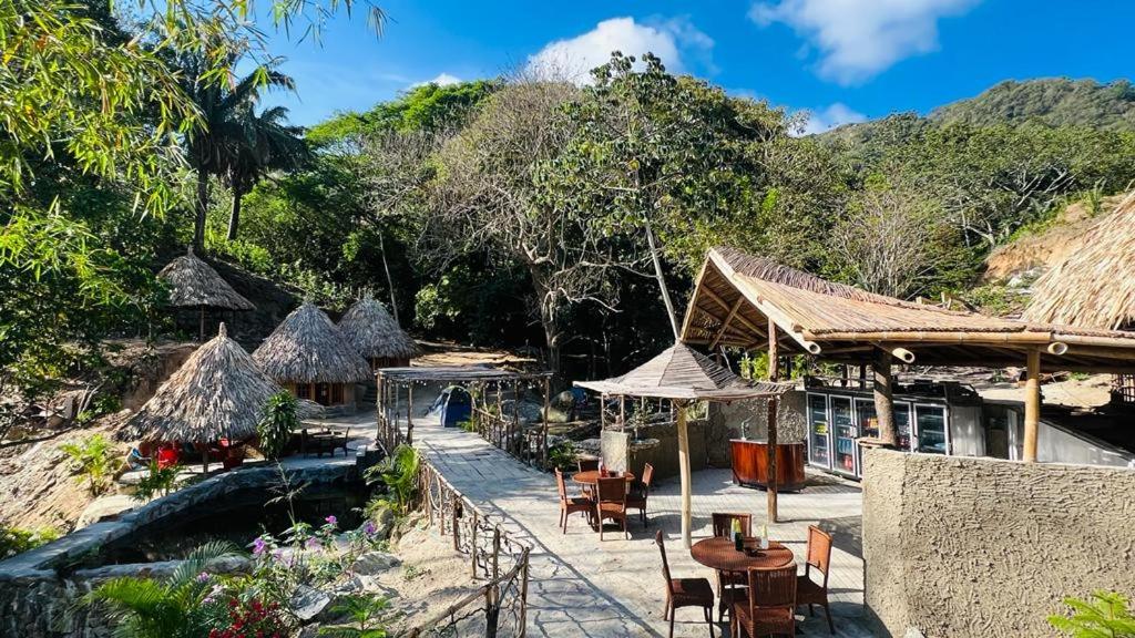 un complejo con mesas, sillas y una piscina en Tawaca ecohotel en Santa Marta