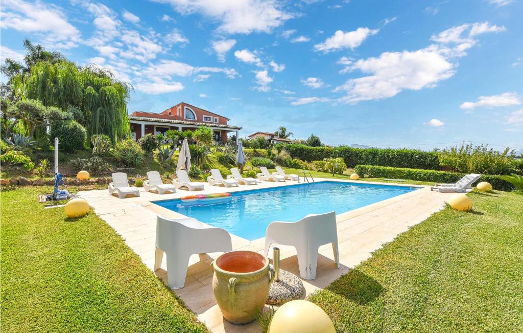 einen Pool mit weißen Stühlen und ein Haus in der Unterkunft Villa Musasealdoge in Partinico