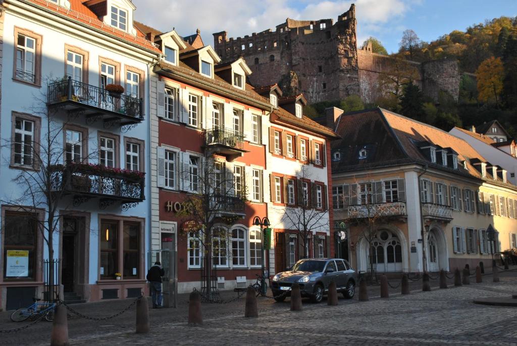 eine Straße mit Gebäuden mit einem Schloss im Hintergrund in der Unterkunft Hotel am Kornmarkt in Heidelberg