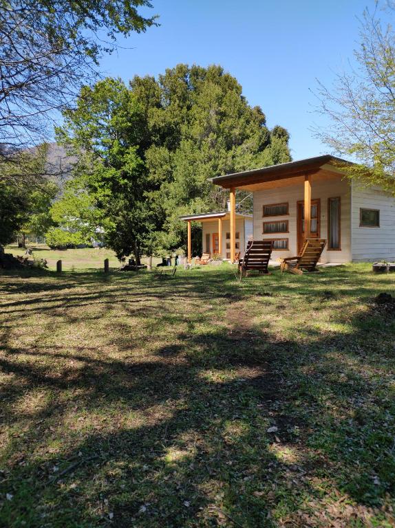 a small house in a field with trees and grass at Piñon House in Melipeuco