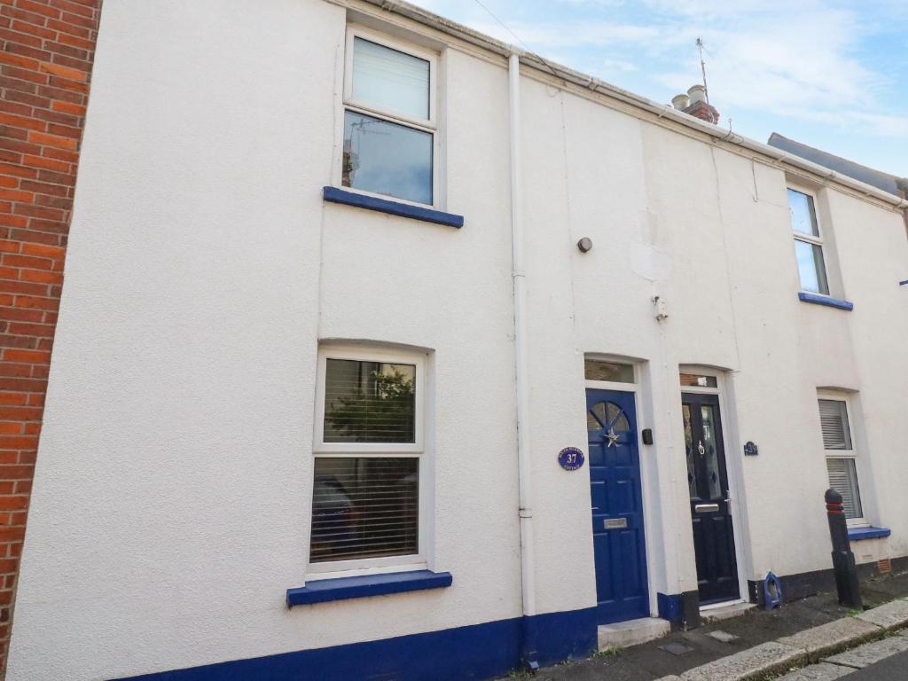 un edificio blanco con puertas y ventanas azules en South Harbour Cottage en Weymouth