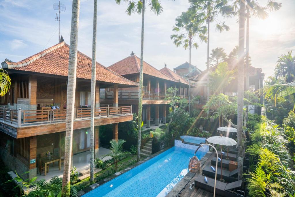 an image of a resort with a swimming pool and palm trees at Budhi Ayu Villas and Cottages Ubud by Mahaputra in Ubud