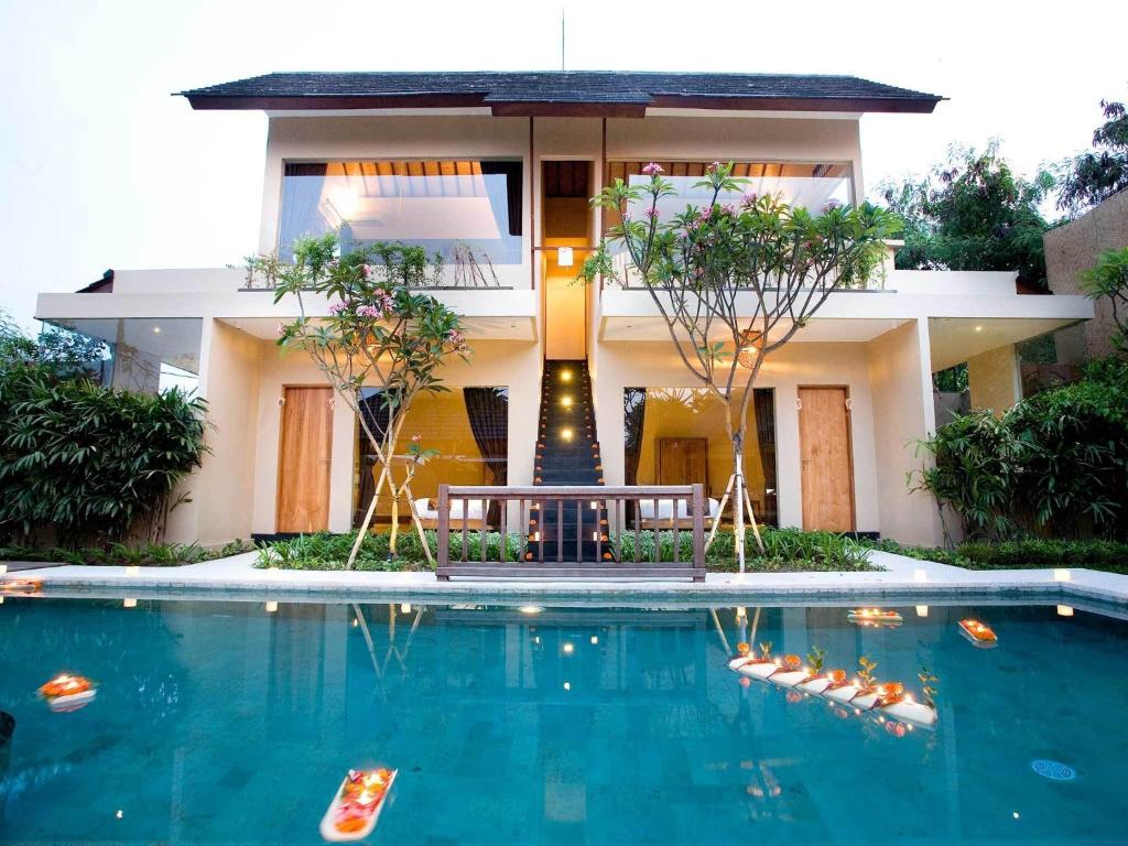 a house with a swimming pool in front of it at Villa Cokelat in Canggu