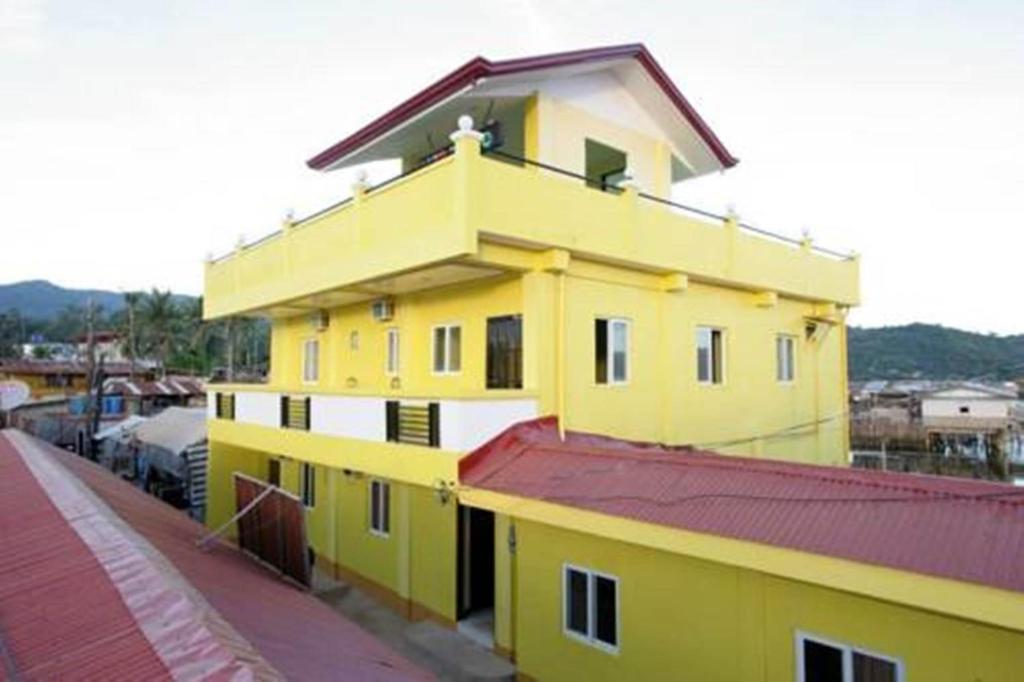 een geel gebouw met een rood dak naast een straat bij Luis Bay Travellers Lodge in Coron