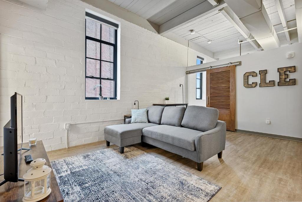 a living room with a couch and a tv at Industrial Loft Apartments in the Beautiful Superior Building Minutes from FirstEnergy Stadium 311 in Cleveland