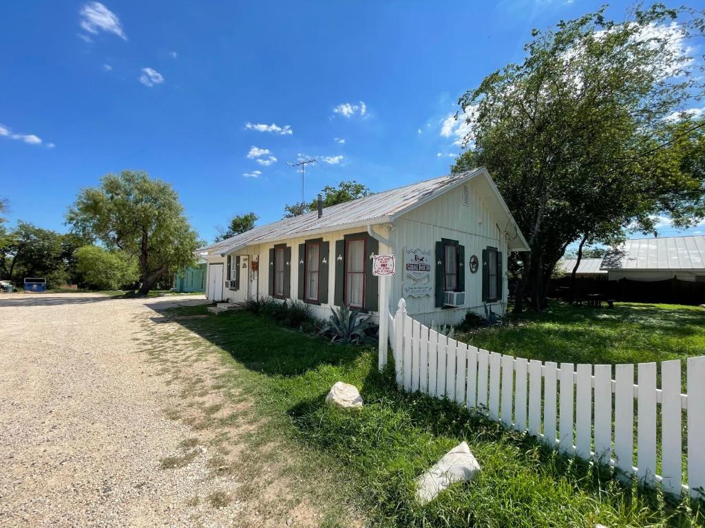 un bâtiment blanc avec une clôture à côté d'une route dans l'établissement Carriage Inn - Cottage, à Bandera