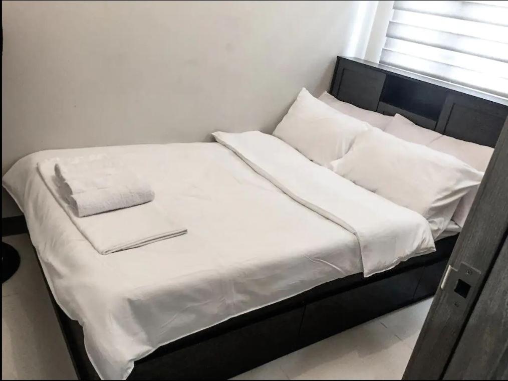 a bed with white sheets and pillows in a room at StayInMyCondo - 8th Condo in Pasay near NAIA Airport, MOA Pasay in Manila