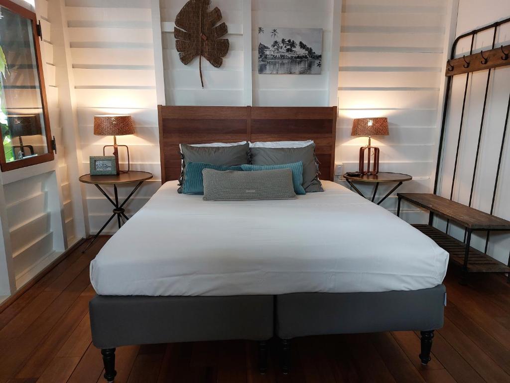 a bed in a room with two tables and two lamps at Couleur Locale Paramaribo in Paramaribo