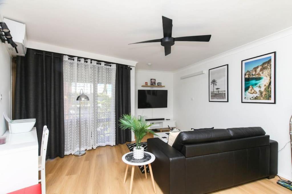 a living room with a black leather couch and a ceiling fan at Modern Apartment Close to the City Centre 16 in Cairns