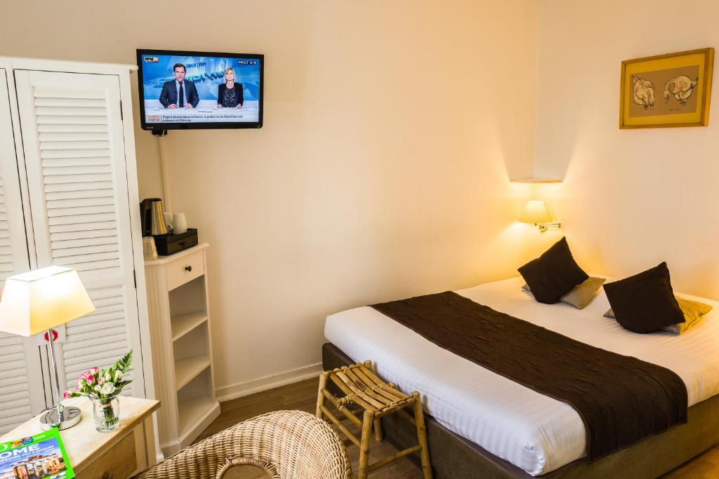 a hotel room with a bed and a tv on the wall at Hotel La Maison des Peyrat in Sarlat-la-Canéda