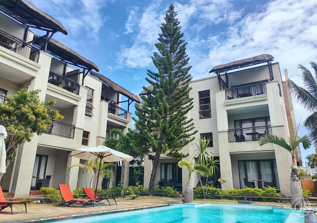 un hotel con piscina frente a un edificio en Grand Bay Suites, en Grand Baie