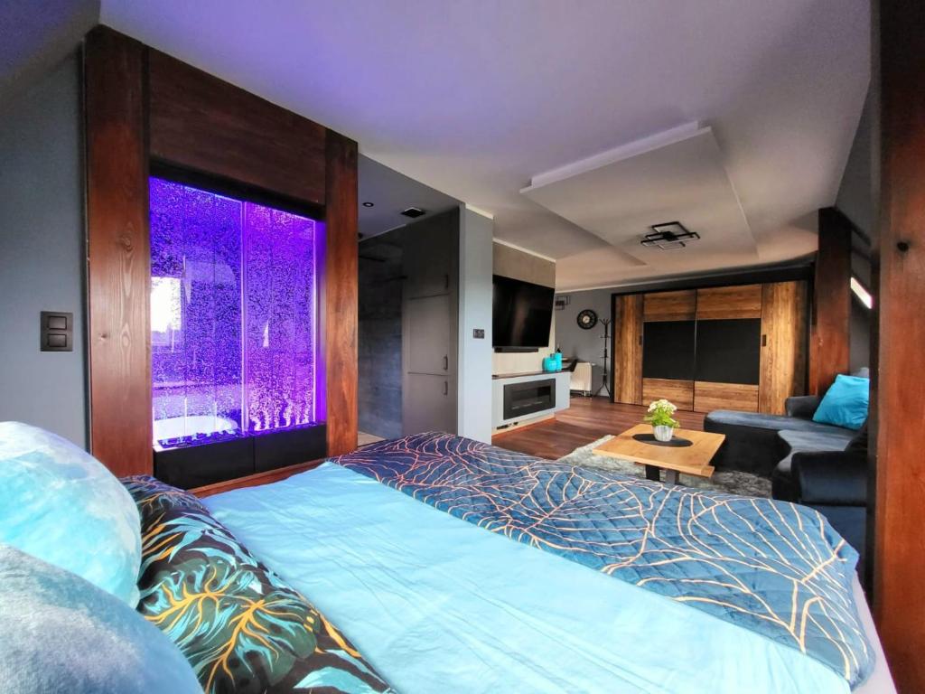 een slaapkamer met een groot bed en een paars verlicht raam bij Lupus Apartamenty in Poznań