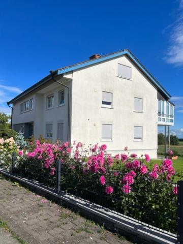 a white house with pink flowers in front of it at Ferienwohnung Maier in Kreenheinstetten