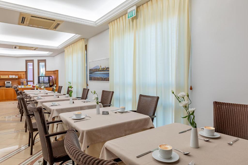 a row of tables in a restaurant with white tablecloths at Hotel Sabbia d'Oro in San Vito lo Capo