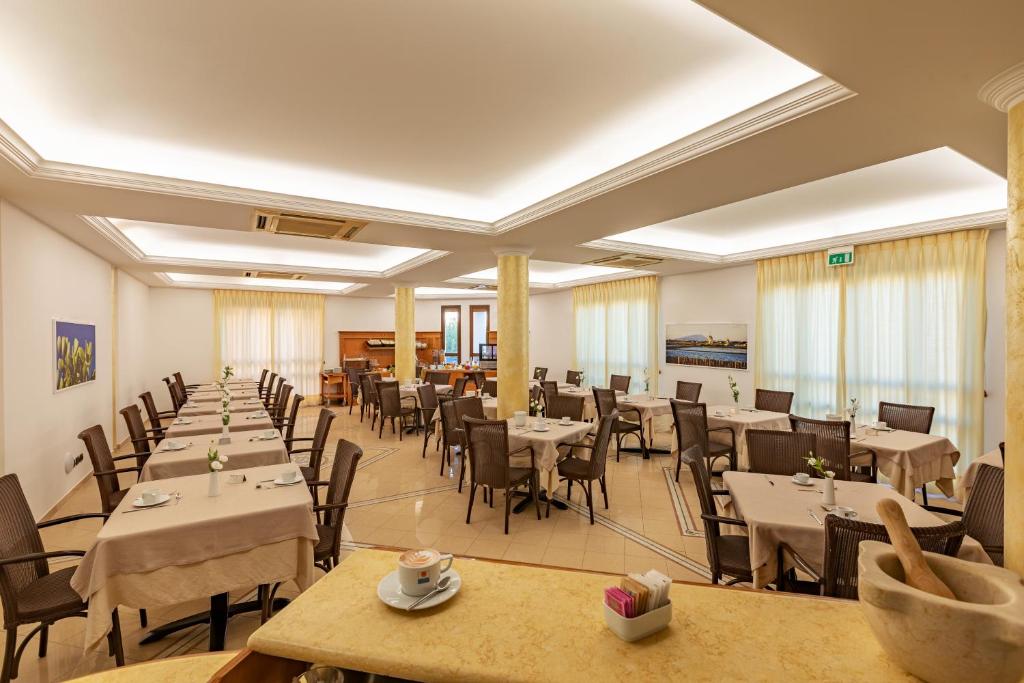 a restaurant with tables and chairs in a room at Hotel Sabbia d'Oro in San Vito lo Capo