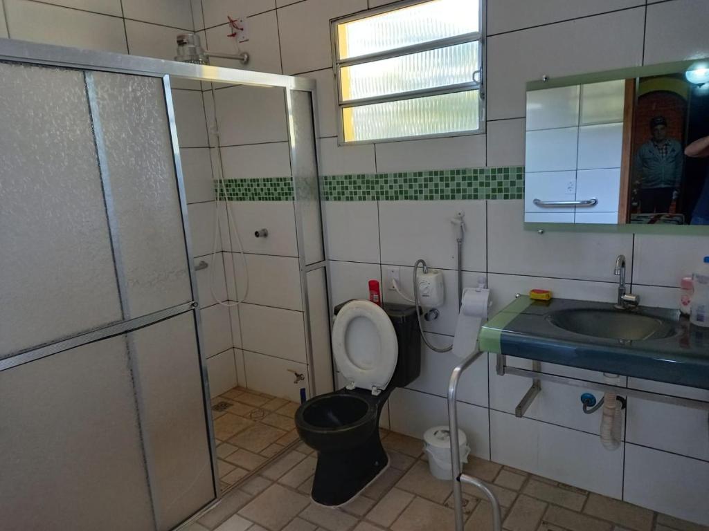 W łazience znajduje się toaleta, umywalka i lustro. w obiekcie Casa de campo serrana, alegre e com piscina w mieście Lindóia
