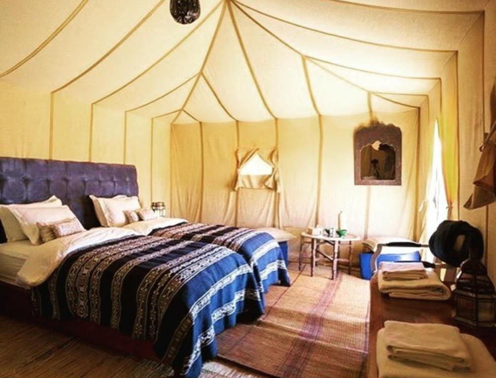 Sahara Luxury Tented Camp في مرزوقة: غرفة نوم بسرير في خيمة