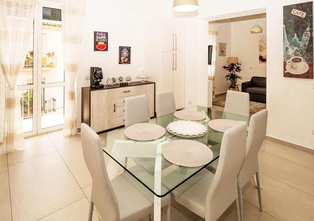 uma sala de jantar e sala de estar com uma mesa de vidro e cadeiras em Amantea Apartment THE NEW em Amantea