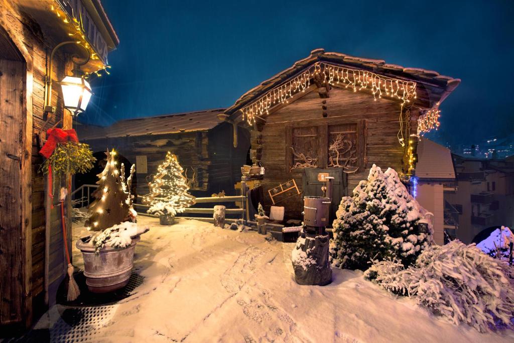 a house decorated with christmas lights in the snow at Hotel Romantica in Zermatt
