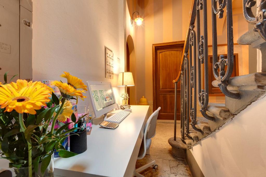een bureau met een laptop en een vaas met bloemen bij Sleep Tight Florence Apartment in Florence