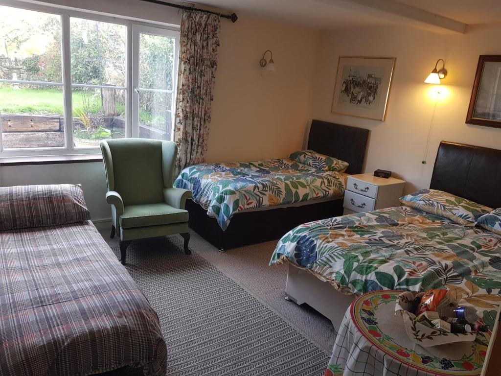 a room with two beds and a chair and a window at The Old Sun private cottage in Frome