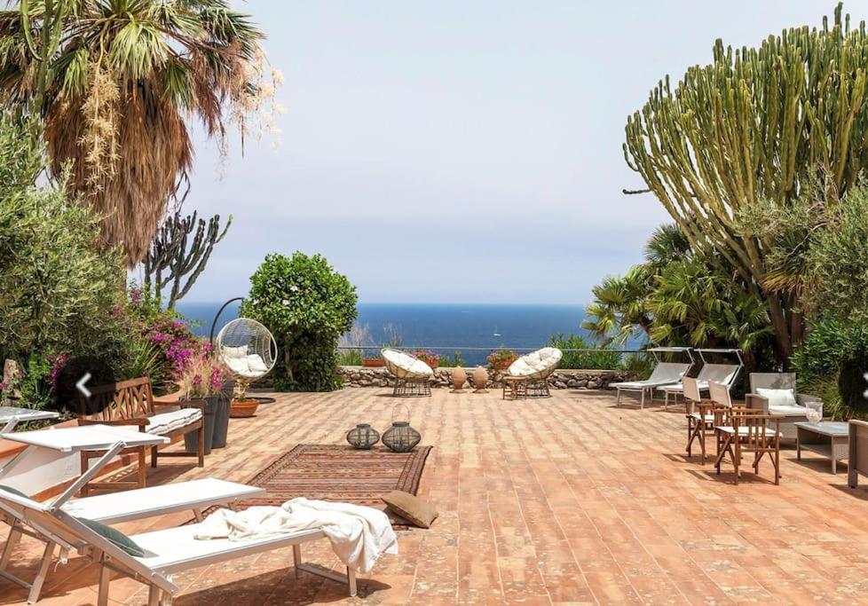 a patio with chairs and tables and the ocean at Cala Bianca (The One&Only) in Castellammare del Golfo