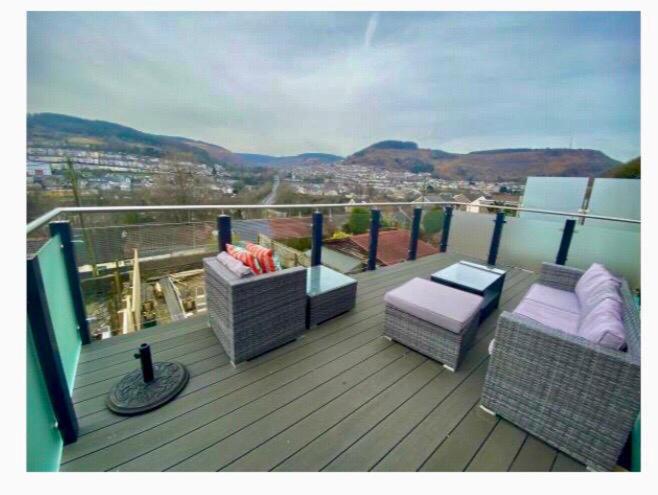 a balcony with two wicker chairs and a table at Valley Views in Llwyn-y-pia