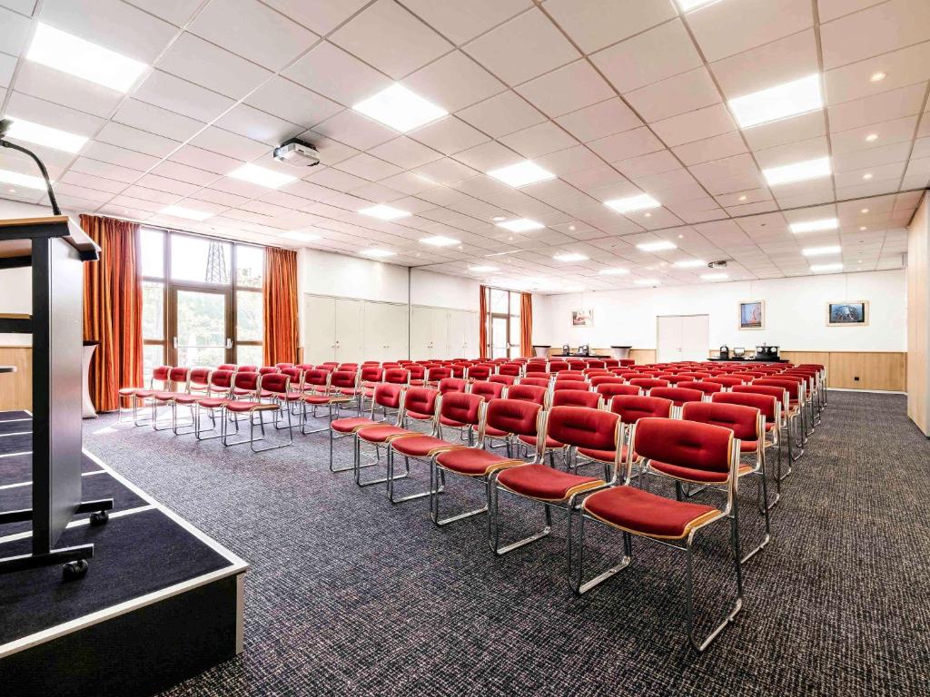 uma sala vazia com cadeiras vermelhas numa sala de aula em Mercure Tours Sud em Joué-lés-Tours