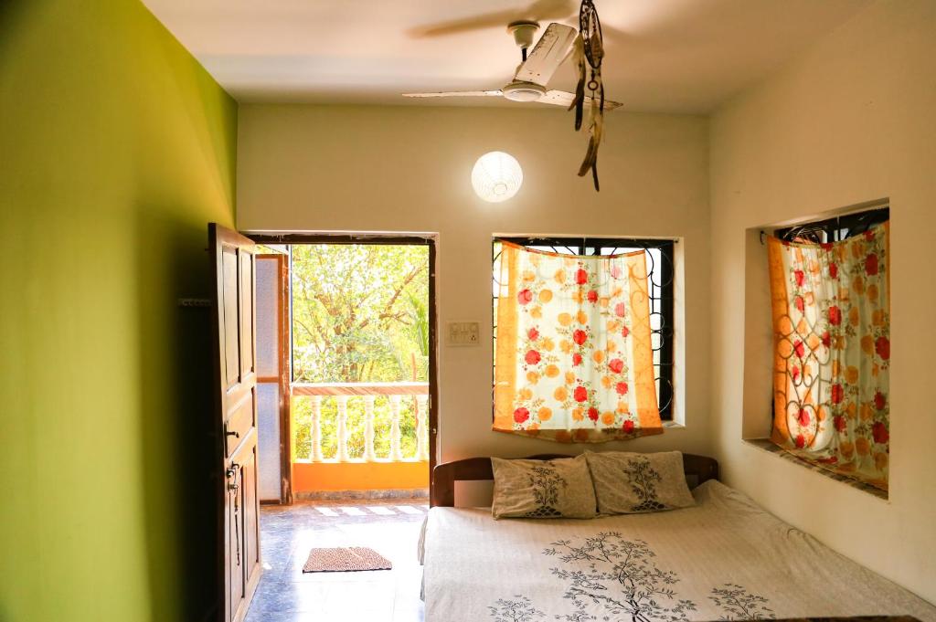a bedroom with a bed and two windows at Dreamcatcher House & Hostel at Arambol Beach in Arambol