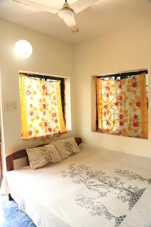 a bedroom with two windows with curtains and a bed at Dreamcatcher House & Hostel at Arambol Beach in Arambol