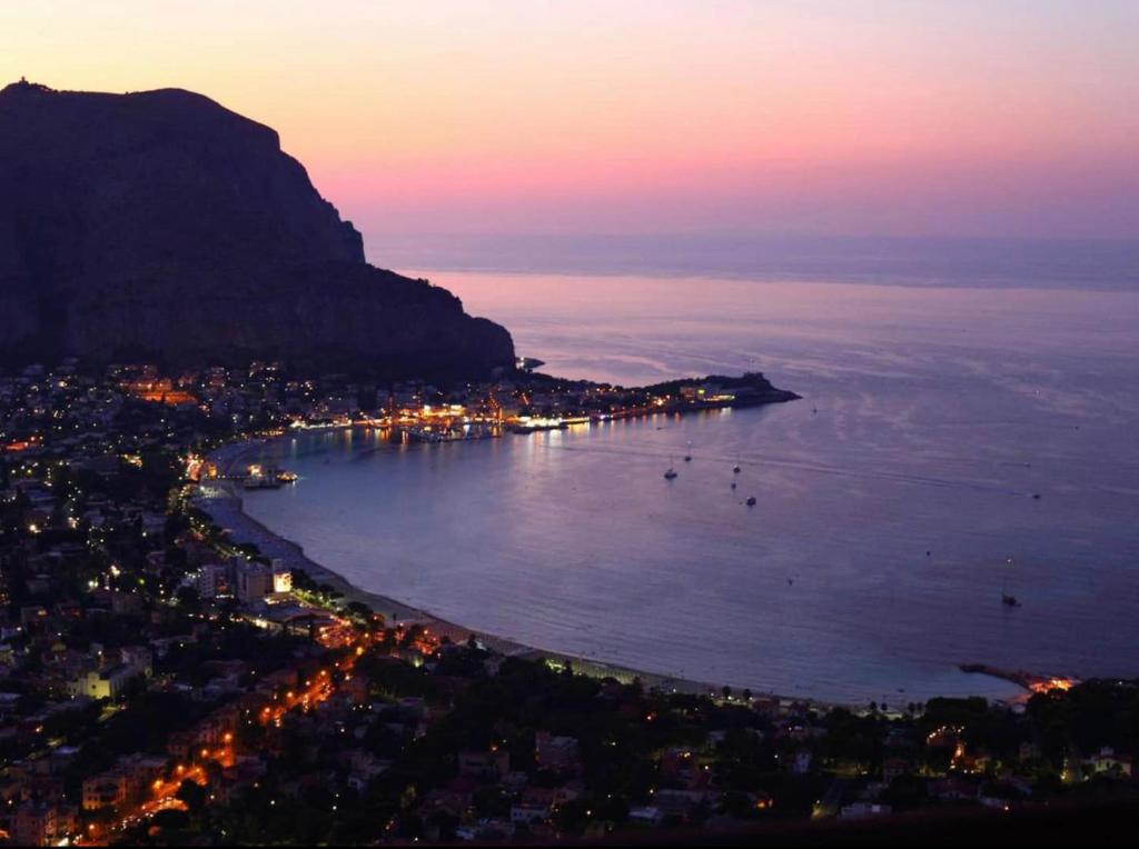 a view of a city and the ocean at night at AR Palace Hotel - Palermo in Isola delle Femmine