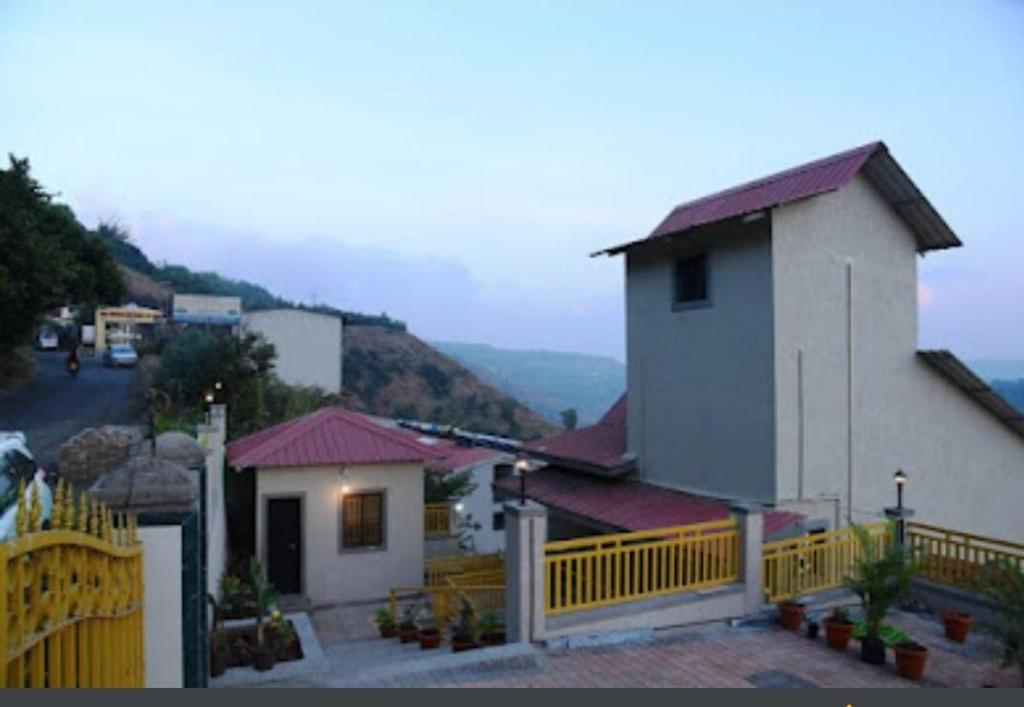 a small white building with a yellow fence at Rozaan Villa Valley View in Mahabaleshwar