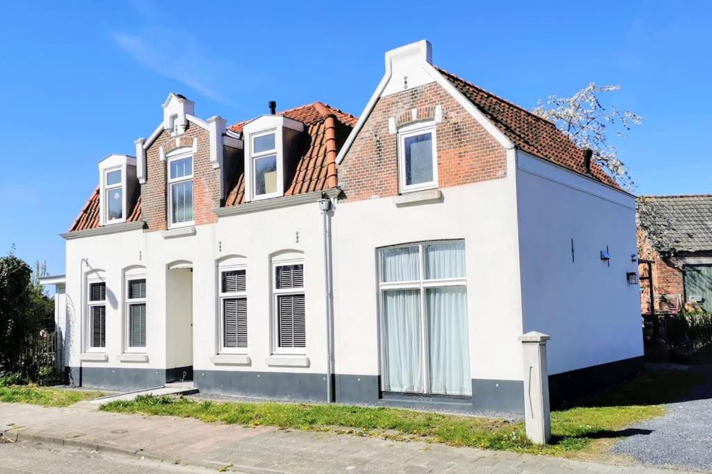 uma casa branca com um telhado vermelho em Volledig gerenoveerde luxe gastsuite met ontbijt em Vlissingen