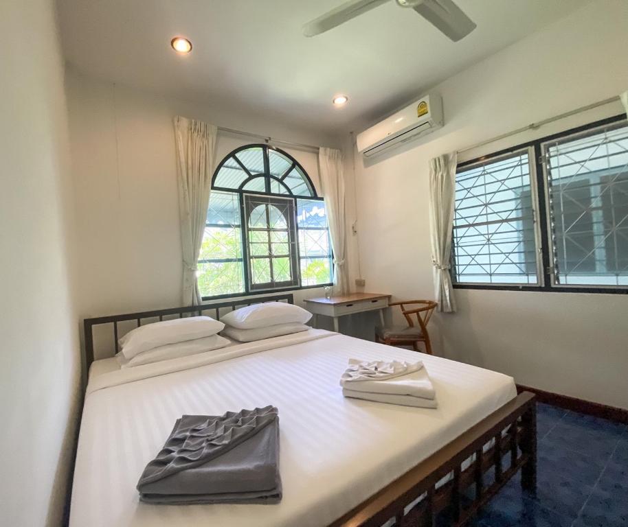 Karon House 15C في شاطئ كارون: غرفة نوم بسرير ابيض كبير عليها شنطتين