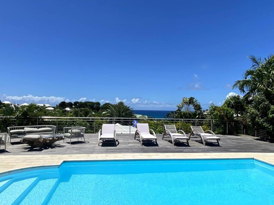 a pool with chaise lounge chairs at Villa Anse Vinaigri - Plage à pieds in Le Gosier