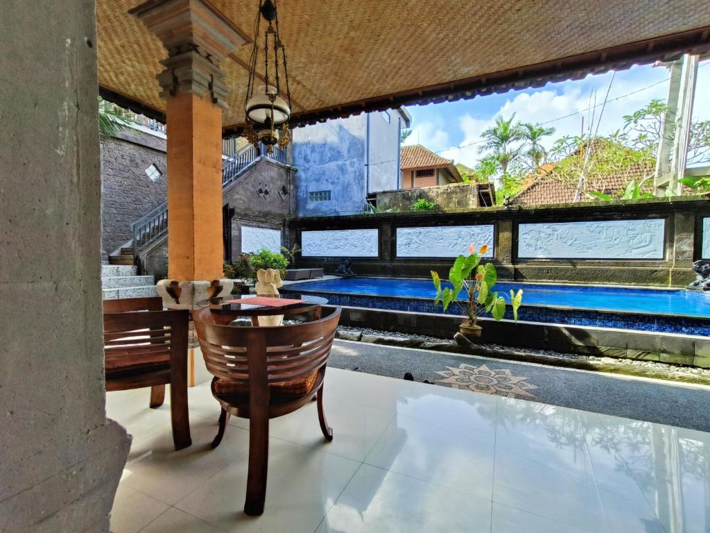 Warji House 2 Bisma في أوبود: غرفة مع مسبح وطاولة وكراسي