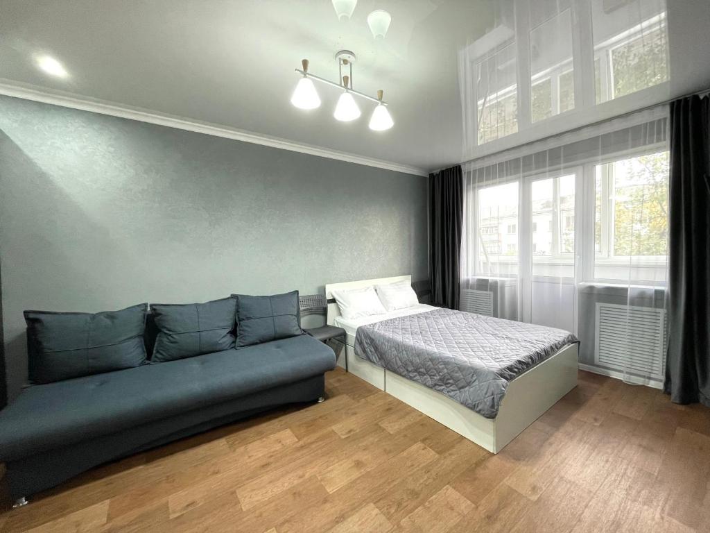 a bedroom with a bed and a couch at Квартира целиком в центре 4 спальных места in Petropavlovsk