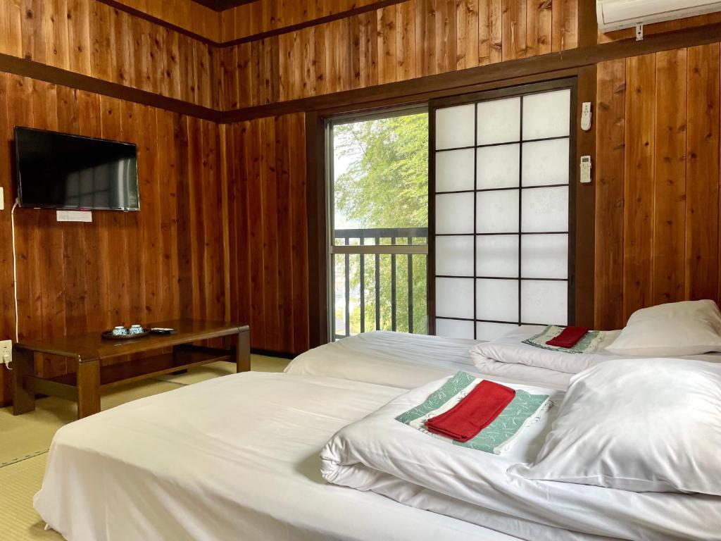 a bedroom with two beds and a tv and a window at 旅館 竹屋 Takeya in Yufuin