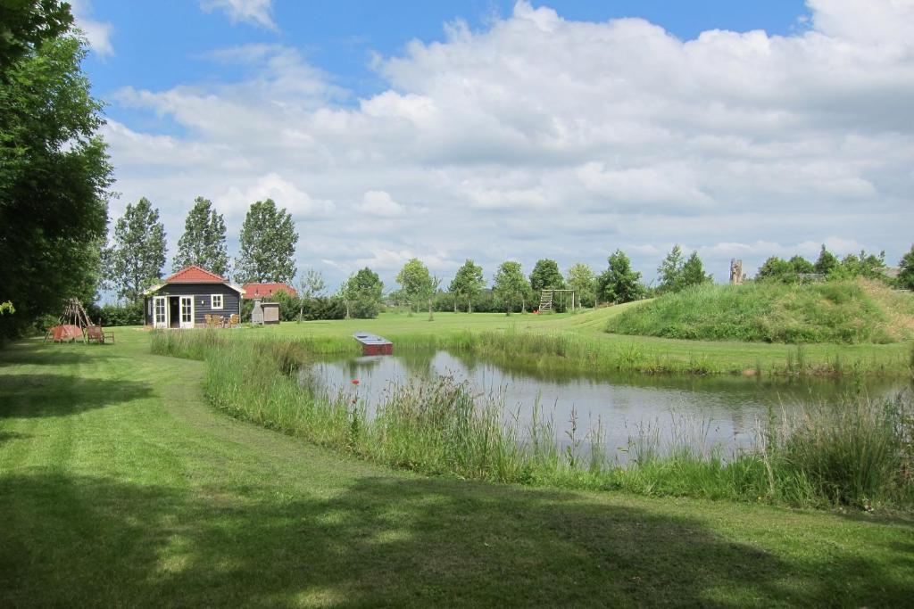 un pequeño estanque con una casa en medio de un campo en Park Nieuwgrapendaal, en Terwolde