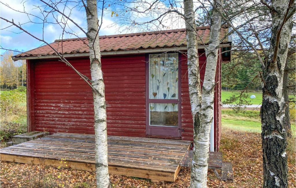 une petite maison rouge avec une terrasse couverte en bois dans l'établissement Cozy Home In Ambjrnarp With Kitchen, à Ambjörnarp