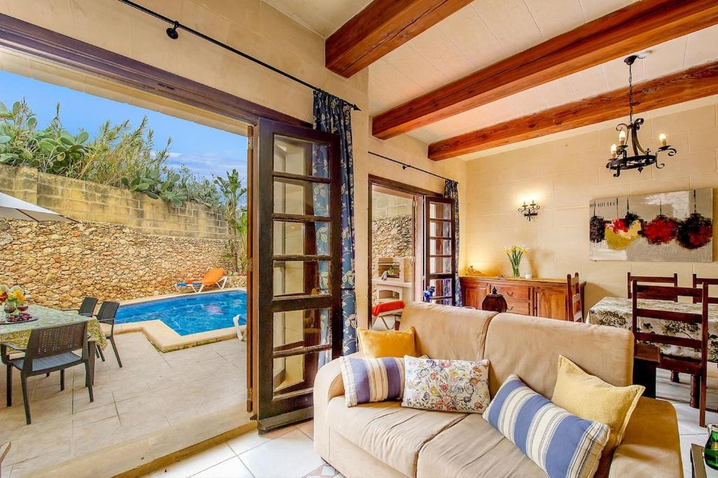 a living room with a couch and a sliding glass door at Razzett ta' Leli Holiday Home in Xagħra