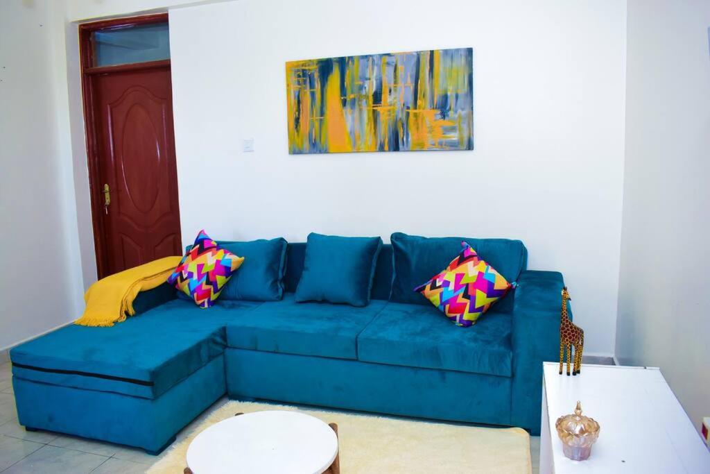 un sofá azul con almohadas coloridas en la sala de estar. en Rorot 2 bdrm stay located Annex home away(bright), en Eldoret