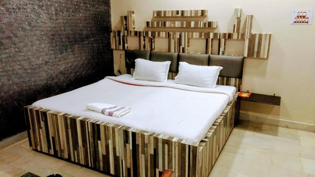 1 cama grande con sábanas blancas y almohadas. en THE PRESTIGE HOTEL & CONVENTION, en Rourkela