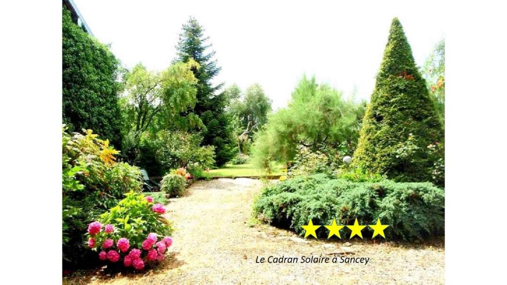een tuin met bloemen en bomen en een pad bij Charme Le Cadran Solaire classé 4* in Sancey-le-Long