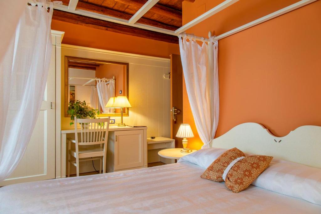 a bedroom with a bed and a desk and a chair at Hotel Calvi-Ristorante Mainor in Vittorio Veneto