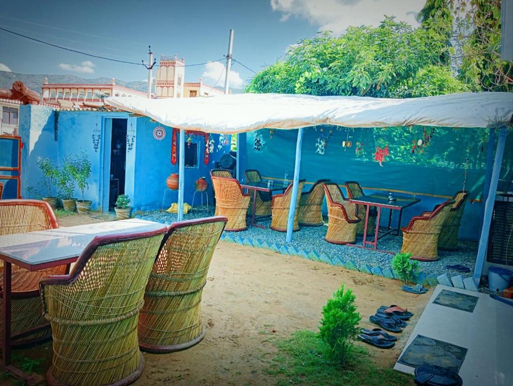 ein blaues Haus mit einem Tisch und Stühlen unter einem Zelt in der Unterkunft Veera's Hostel in Pushkar